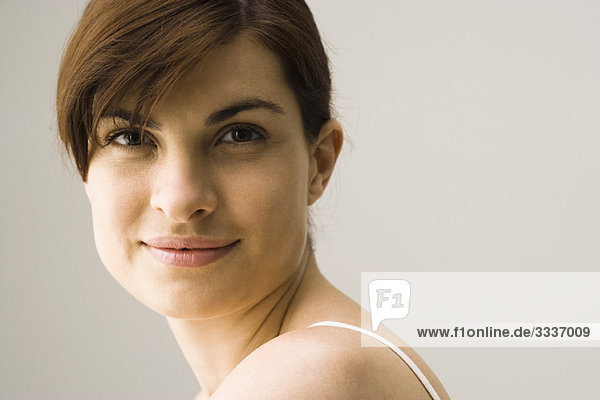 Young woman smiling over shoulder  portrait