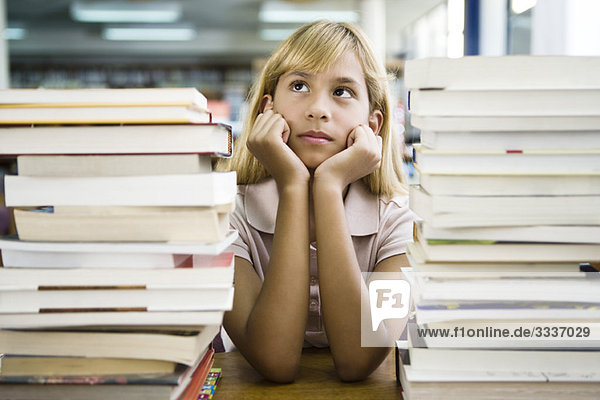 Junges Mädchen  das sich auf den Ellenbogen stützt  Tagträume  Bücherstapel im Vordergrund
