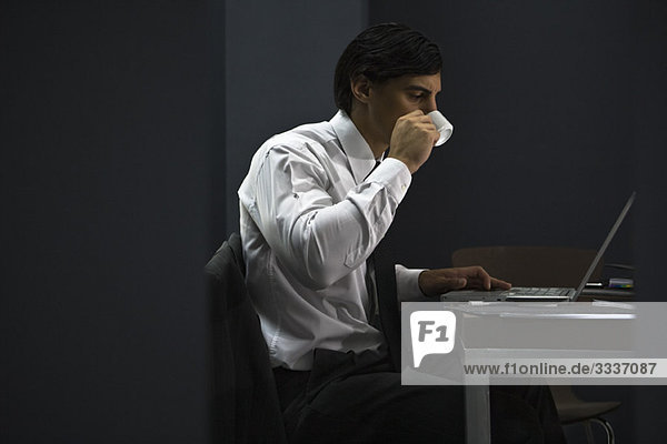 Man in office drinking coffee  working late