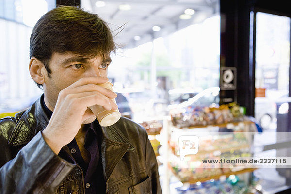 Mann trinkt Kaffee im Convenience Store