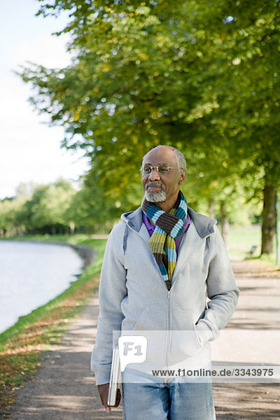 Senior man walking in a park with a laptop  Sweden.