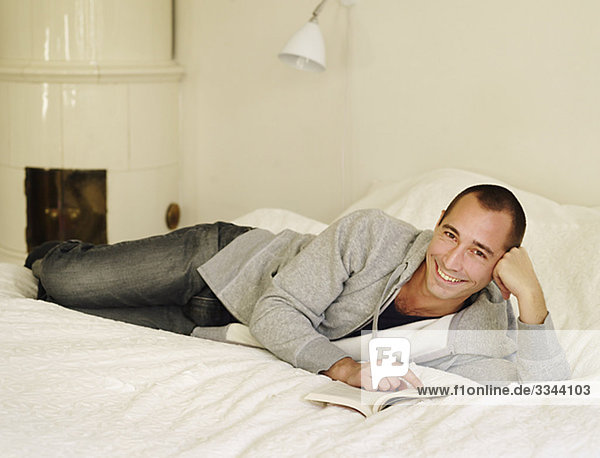 Portrait of a mid-adult Man lesen im Bett  Schweden.