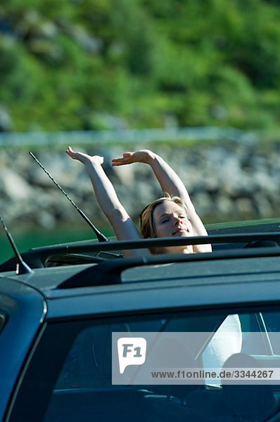 Woman stretching out her arms by a car  Norway.