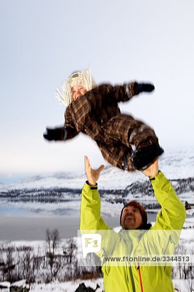 Vater sein Baby in der Luft  Schweden werfen.