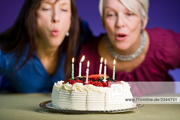 Zwei Frauen mit einem Geburtstagskuchen.
