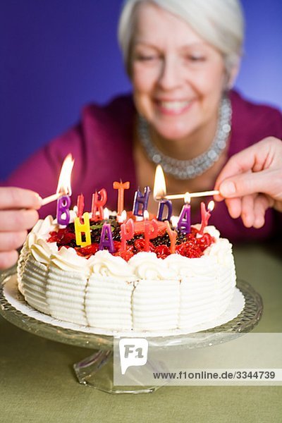 ältere Frau mit einem Geburtstagskuchen.