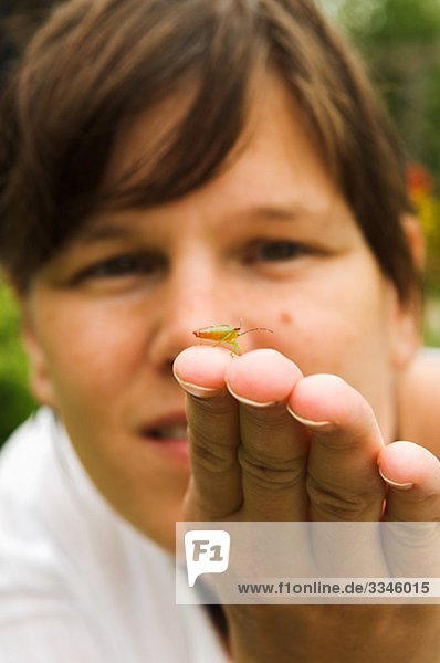 Frau blickt auf ein Insekt  Schweden.