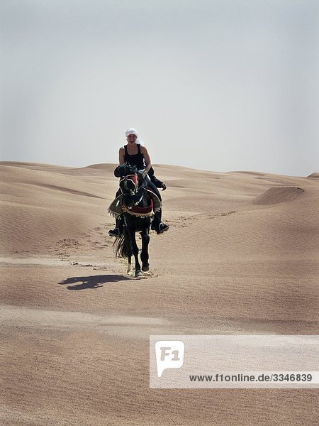 Woman riding a horse in the desert  Tunisia.