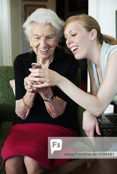Young woman showing elderly lady a cellphone
