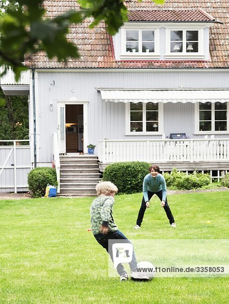 Mutter und Sohn spielen Fußball im Garten