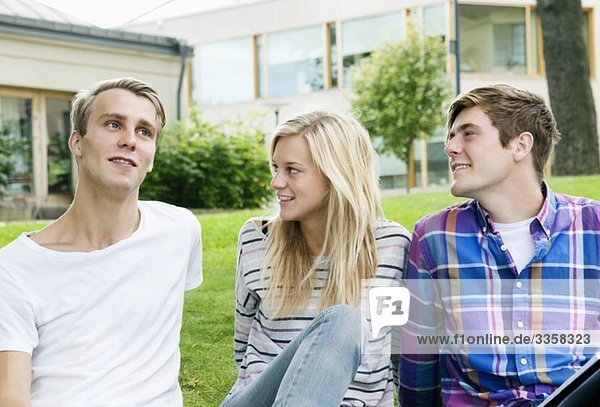 Drei Schüler auf dem Rasen sitzend