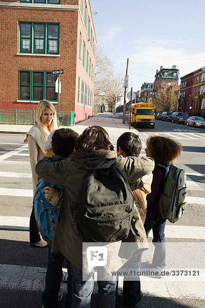 Teacher and children by pedestrian crossing