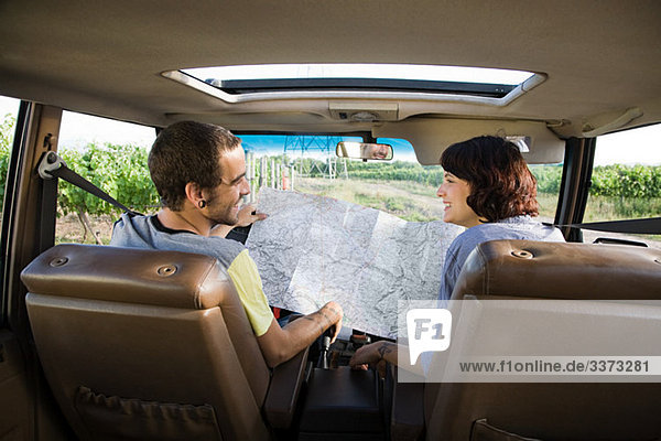 Young couple in vehicle with map