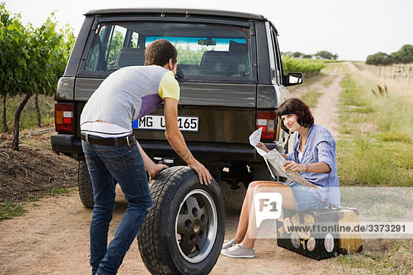Couple by suv with tyre and map