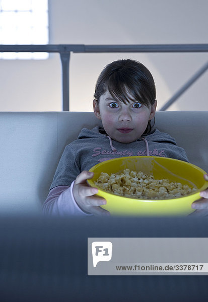 Mädchen mit einer Schüssel Popcorn vor einem Fernseher  Frontalansicht