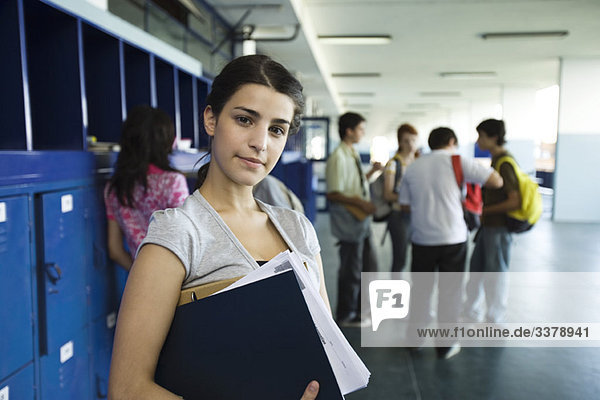 Female high school student standing in hall lined with lockers