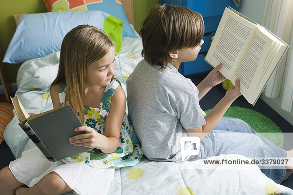 Geschwister lesen zusammen  Mädchen blickt über die Schulter zu Bruder's Buch