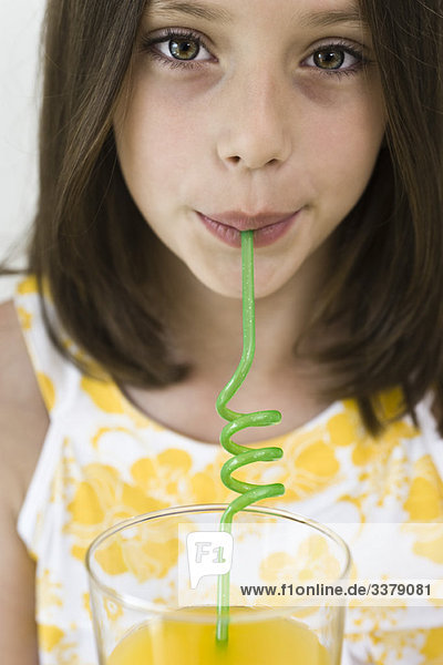 Mädchen trinken Saft durch gelockten Strohhalm
