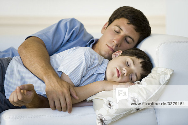 Vater und Sohn schlafen zusammen auf dem Sofa.