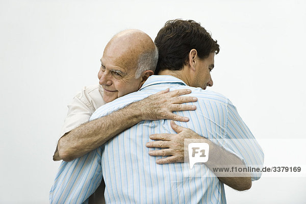 Älterer Mann umarmt erwachsenen Sohn