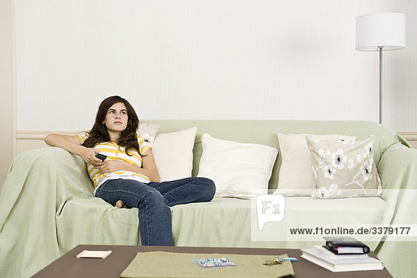 Teenage girl with remote control contemplatively looking away