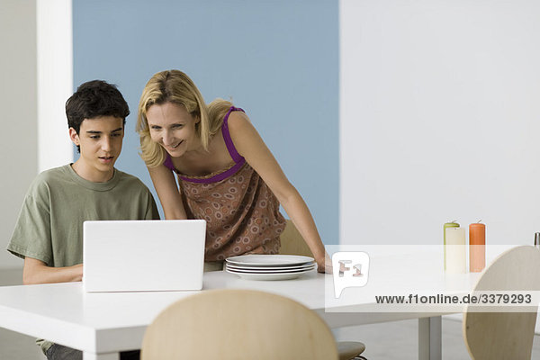Teenage boy showing mother laptop computer