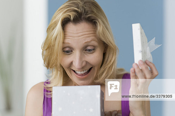 Woman with look of surprise opening gift