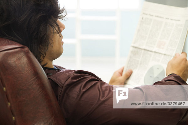 Young man relaxing with newspaper