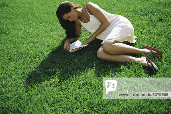 Junge Frau auf Gras liegend Lesebuch