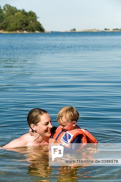 Boy in eine Schwimmweste Baden mit seiner Mutter  Schweden.