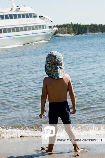 Boy am Strand Blick auf einem Boot  Schweden.