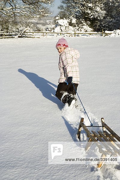 Junges Mädchen zieht Schlitten im Schnee