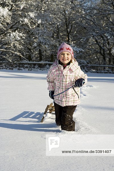 Young girl pulling sledge in snow