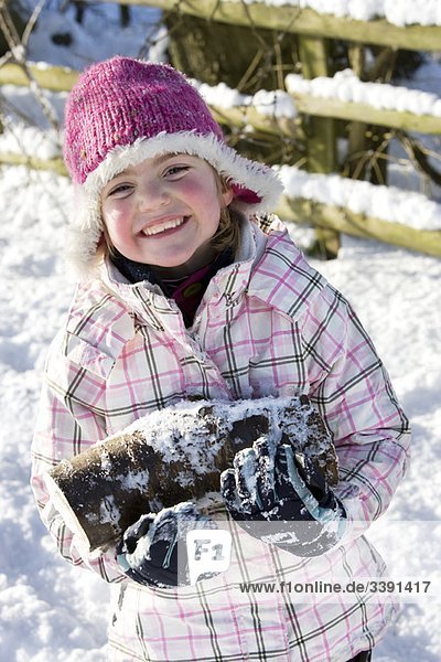 Junges Mädchen mit Baumstämmen im Schnee