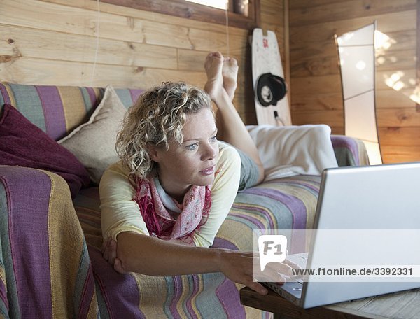 Frau in einem Strandhaus  mit Hilfe des Computers