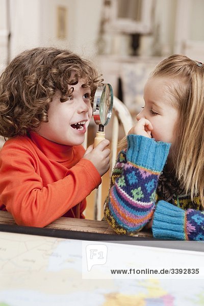 zwei Kinder spielen mit Lupe