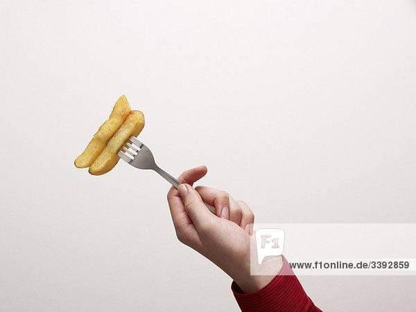 Hand hält Chips auf einer Gabel