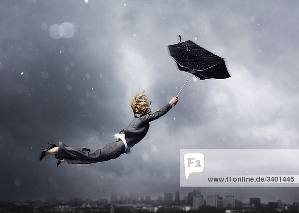 Frau wird von einem Regenschirm weggeblasen