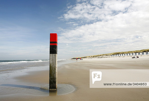 Holzpfosten am Strand von Texel  Strandhäuser im Hintergrund  Niederlande