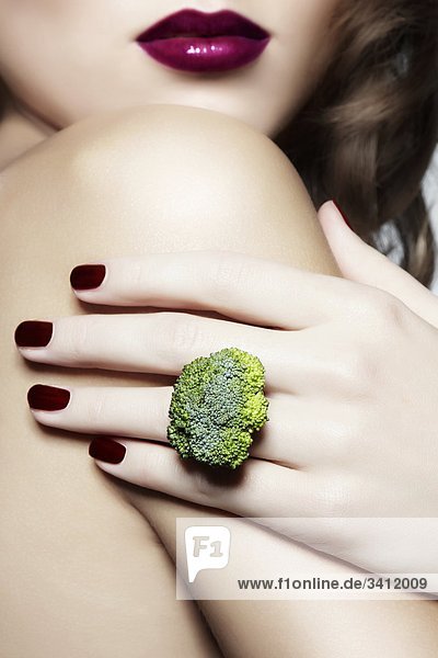 Junge Frau mit einem Ring aus Broccoli mund