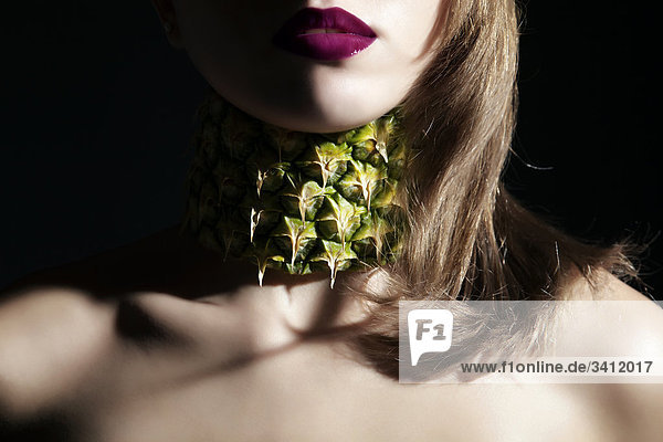Junge Frau mit Halkette aus Ananas mund
