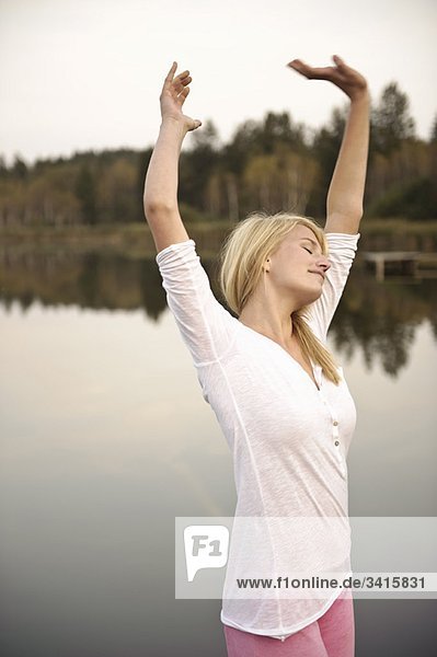 Junge Frau beim Tanzen am See  Stretching