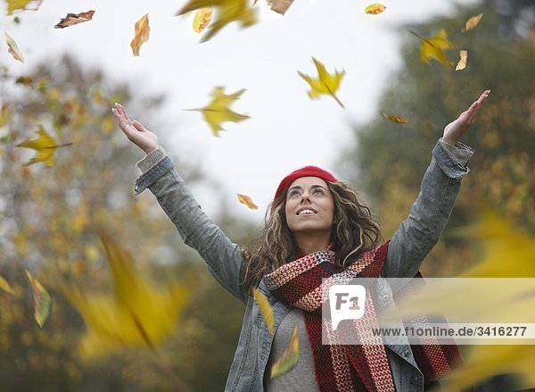 Frau wirft getrocknete Blätter in die Luft