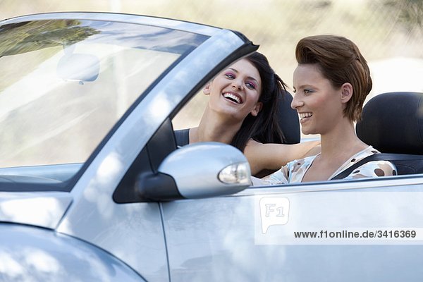 Two women laughing in a convertible car