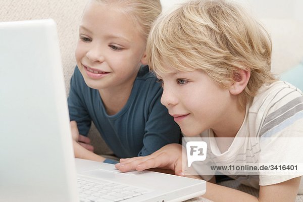 Ein Junge und ein Mädchen  die einen Laptop benutzen.