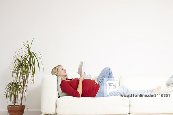 Pregnant woman reading on sofa