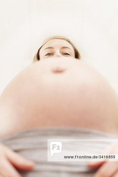 Woman's face looking over pregnant belly