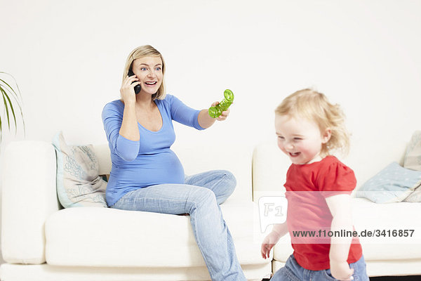 Schwangere Frau am Telefon mit Kleinkind