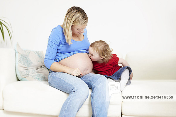Kleinkind küsst schwangeren Bauch