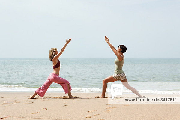 Zwei Frauen Übendes Yoga am Strand